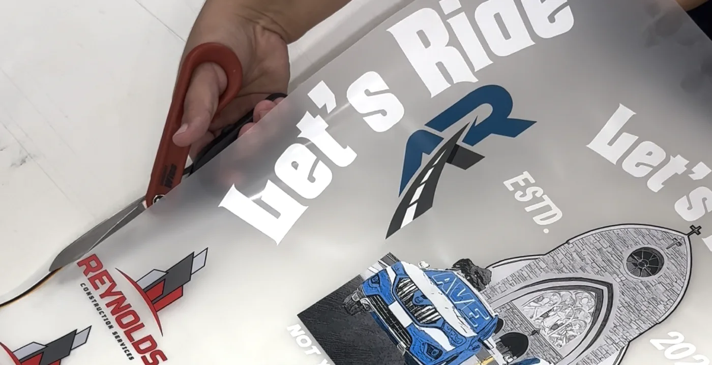 A DTF sheet of client logos being trimmed at Evibes